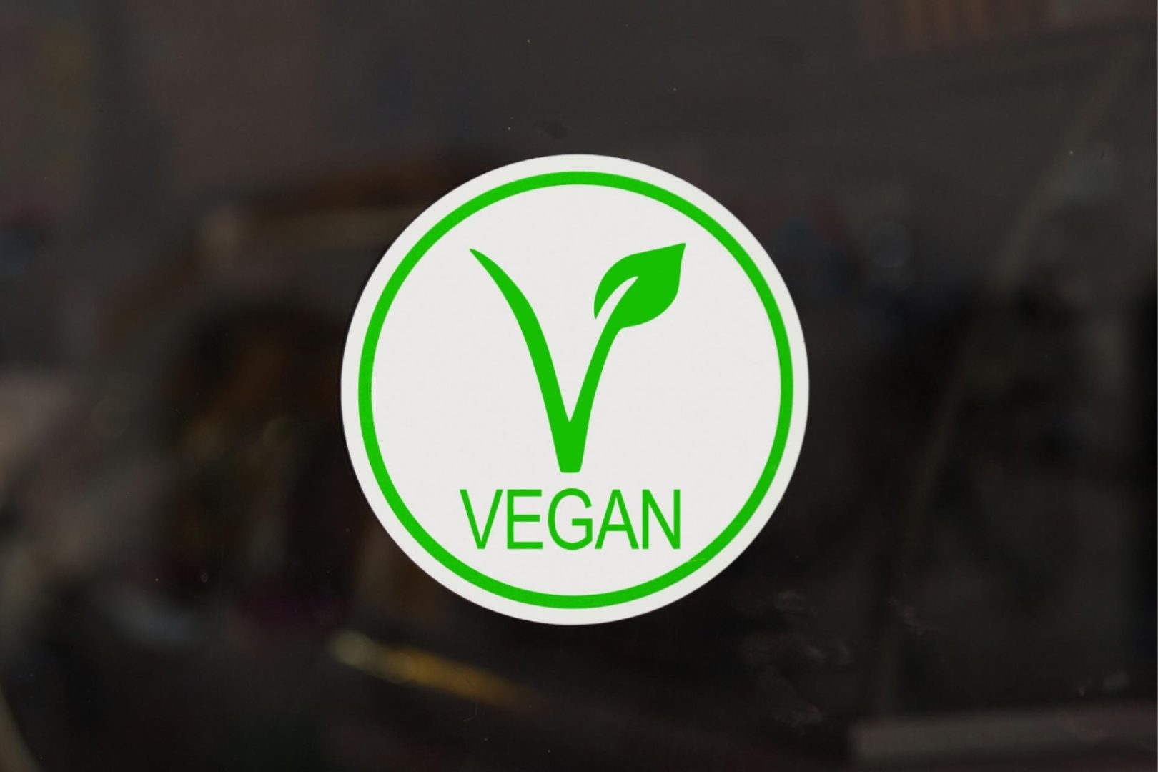 The green vegan logo in a white circle with a dark background around it.