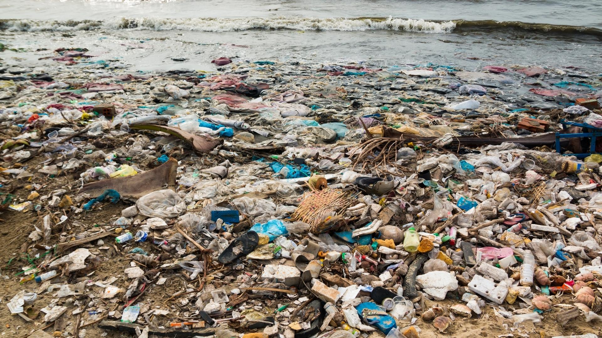 A photo of the shore of a body of water, covered in garbage.