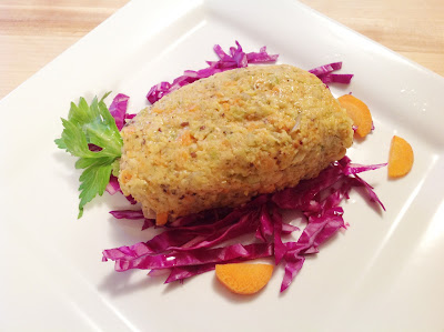 A square white plate holding an oval of veganized gefilte fish on a bed of red cabbage and a few pieces of carrot and parsley.
